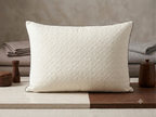 Quilted white pillow on a wooden surface with a neutral background